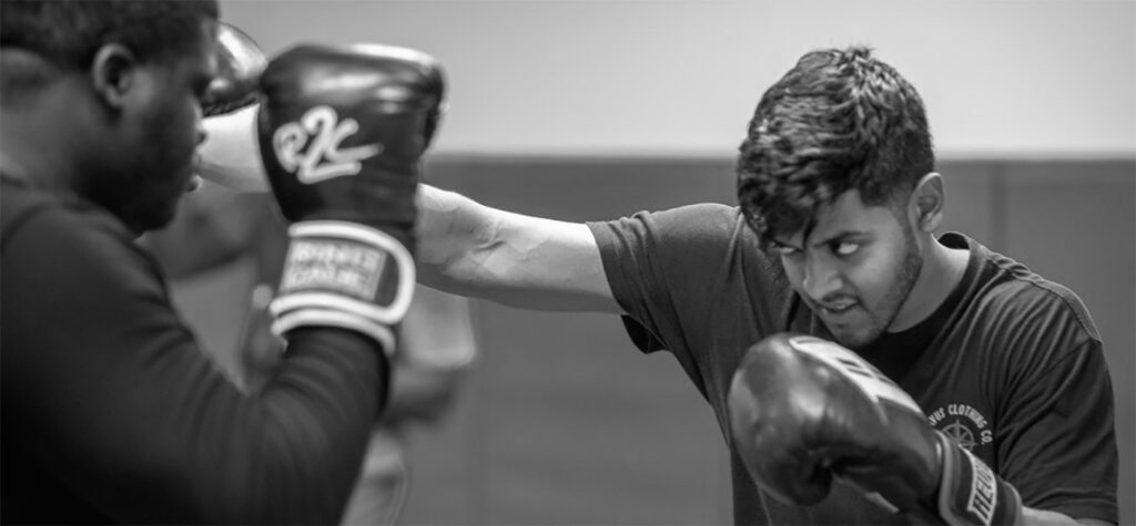 A man throwing a punch at another man with boxing gloves on