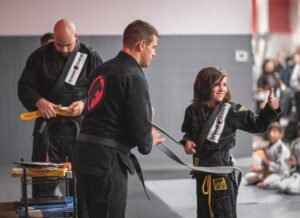 Martial arts instructor awarding a kid with his new belt