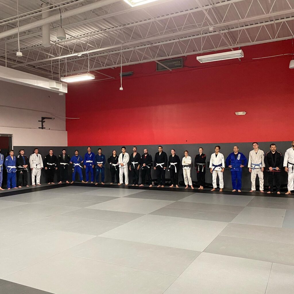 Group of martial arts students lined up around the edges of a mat