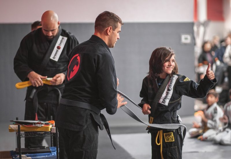 Martial arts instructor awarding a kid with his new belt