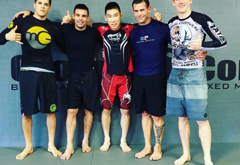 Five men posing and smiling in a martial arts facility